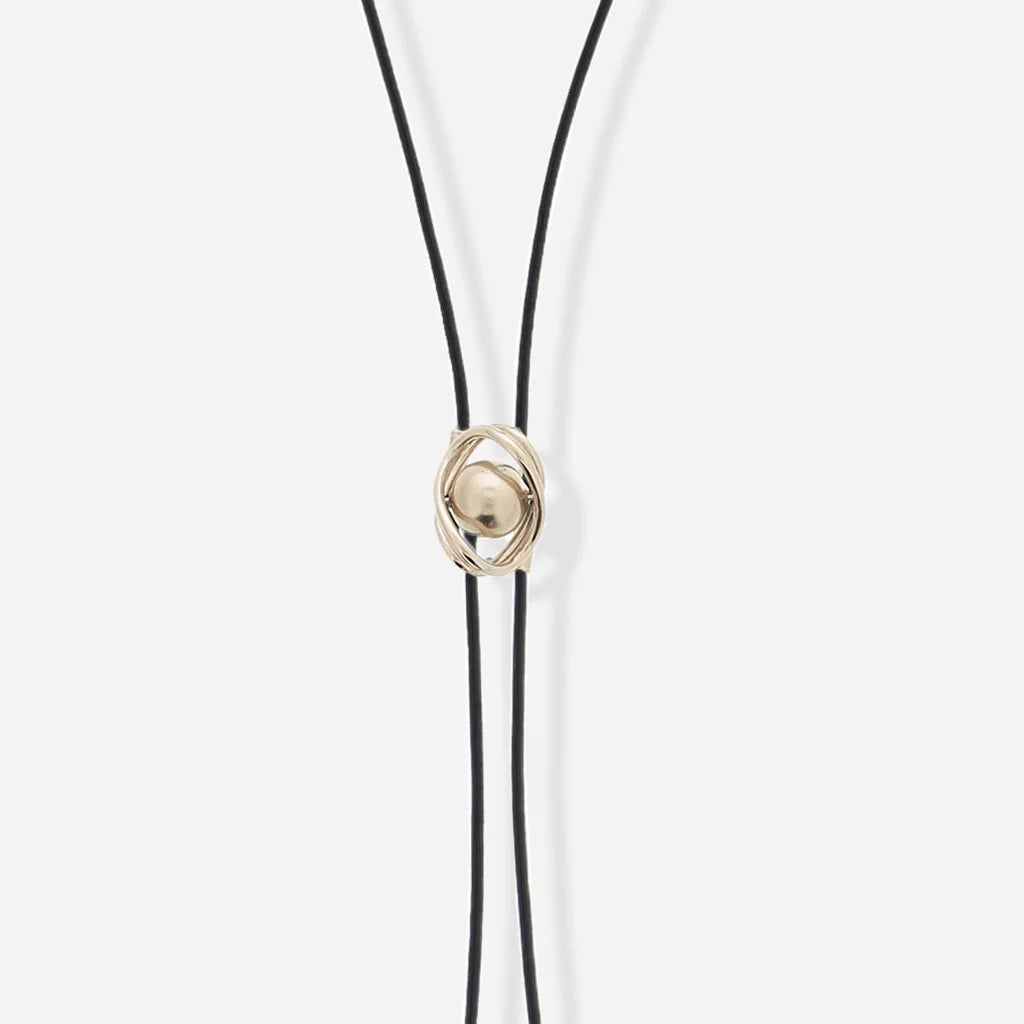 Collier cravate Bolo Anomalie unisexe en cuir noir, avec détail en satin doré et perle de métal dorée.