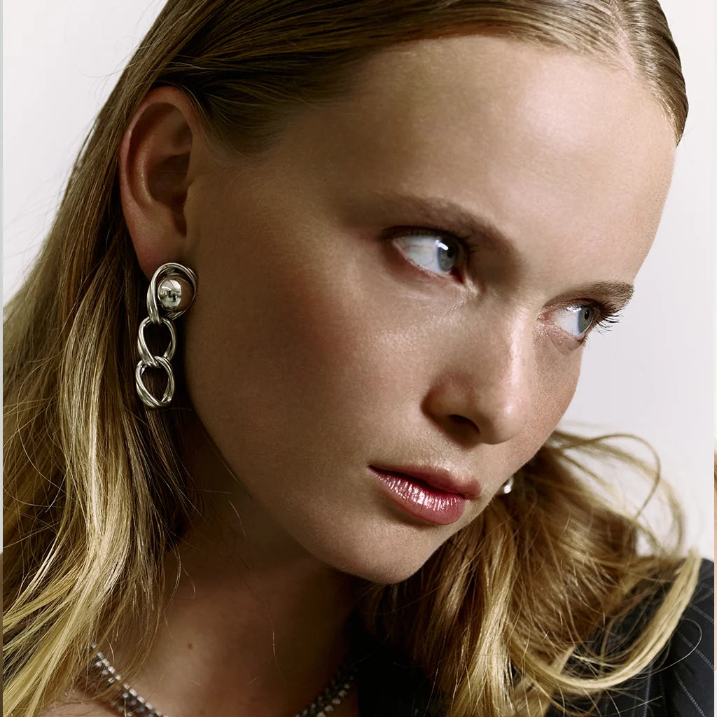 Visage d’une femme portant des boucles d’oreilles perles pendantes Anomalie en métal satiné argenté et perles.