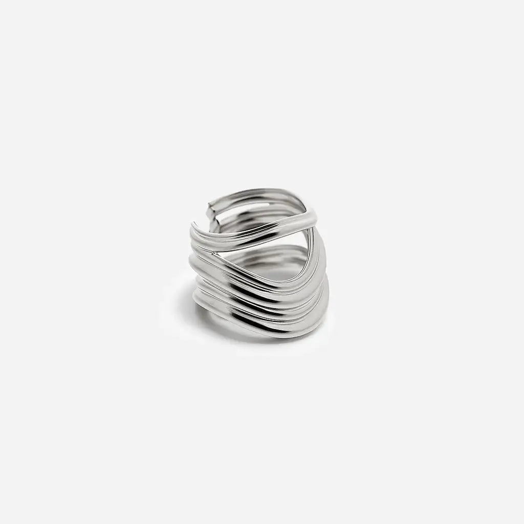 Une bague large Anomalie graphique en métal satiné argenté, composée de plusieurs lignes métalliques volumineuses.