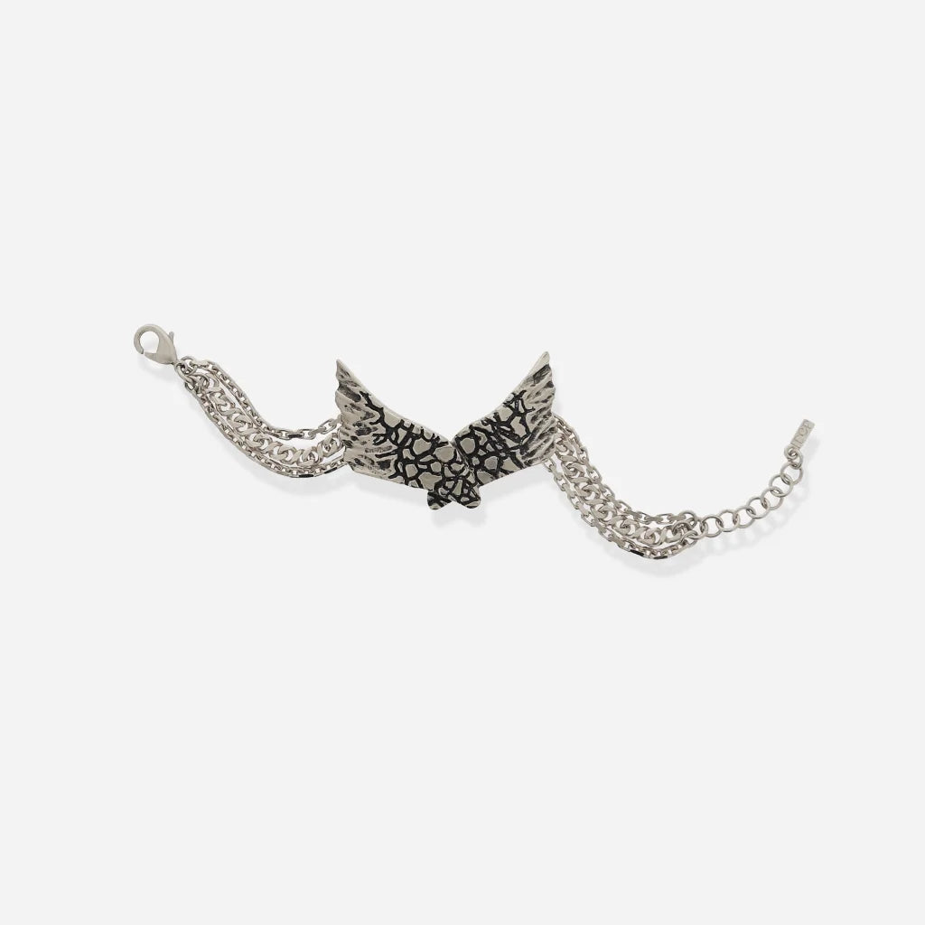 Bracelet ailes Turbulence en vieil argenté, pièce centrale ailée texturée de fissures, avec triple chaîne élégante.