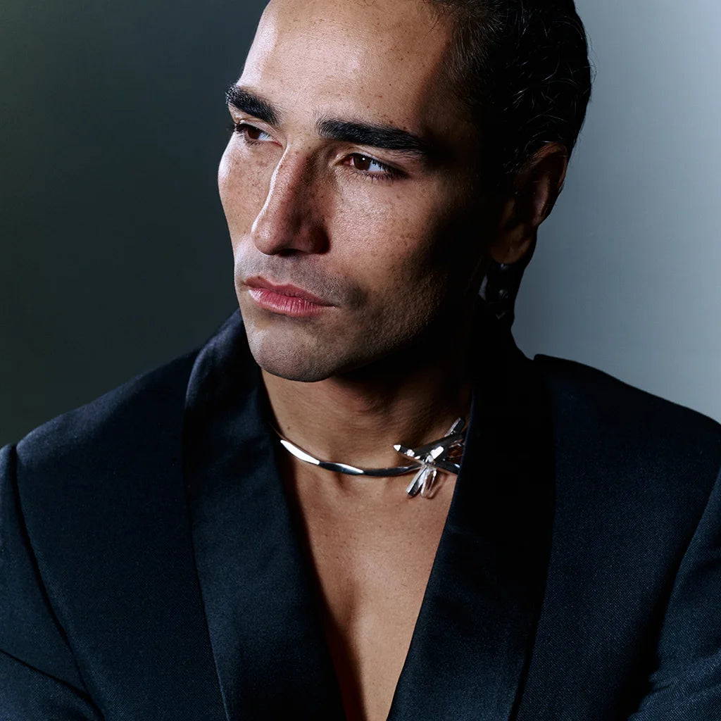 Collier torque Turbulence en métal satiné argenté avec motif cristal de roche, bijou sculptural porté par un homme.