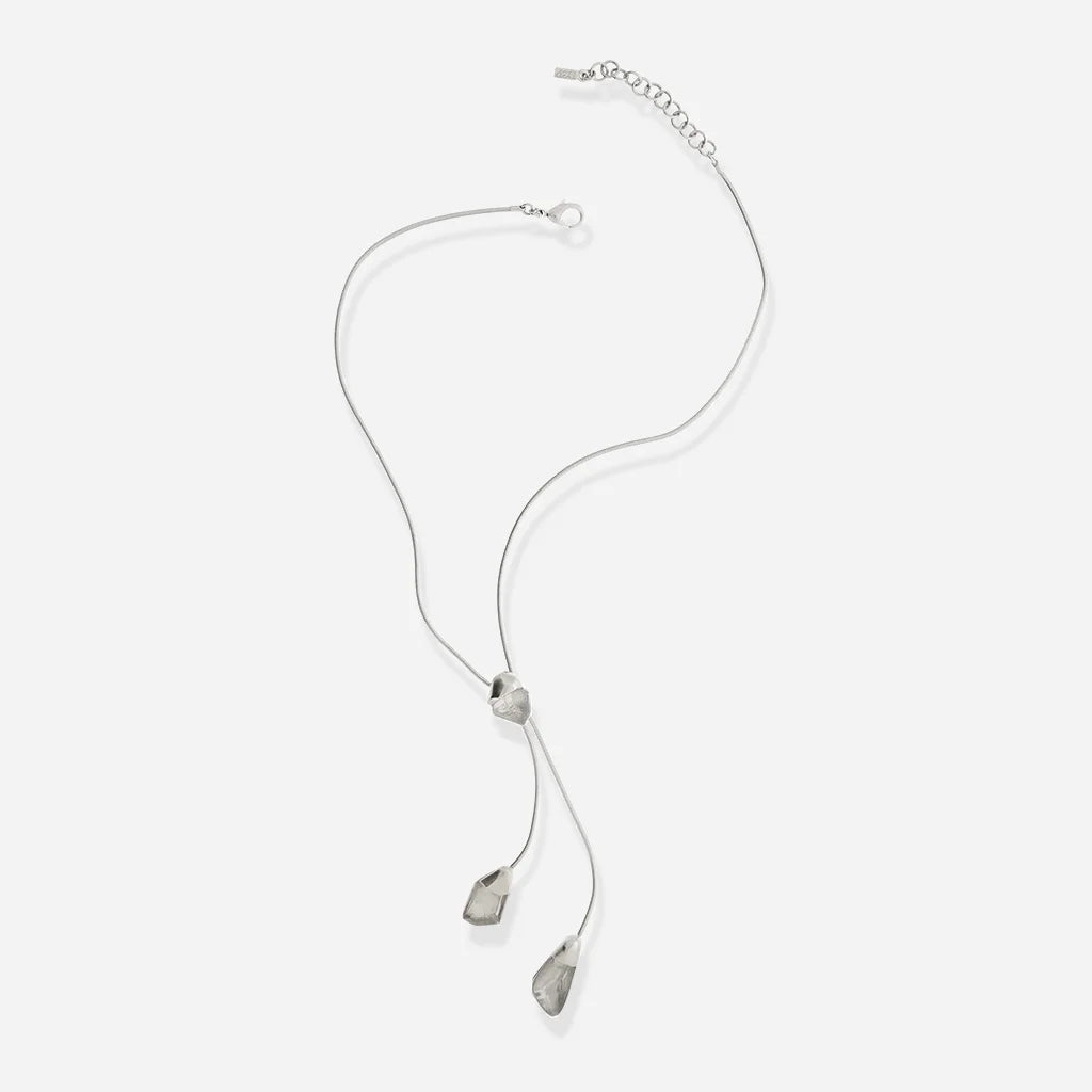 Le collier cravate en métal argenté pour femme présente trois éléments facettés suspendus à une chaîne souple