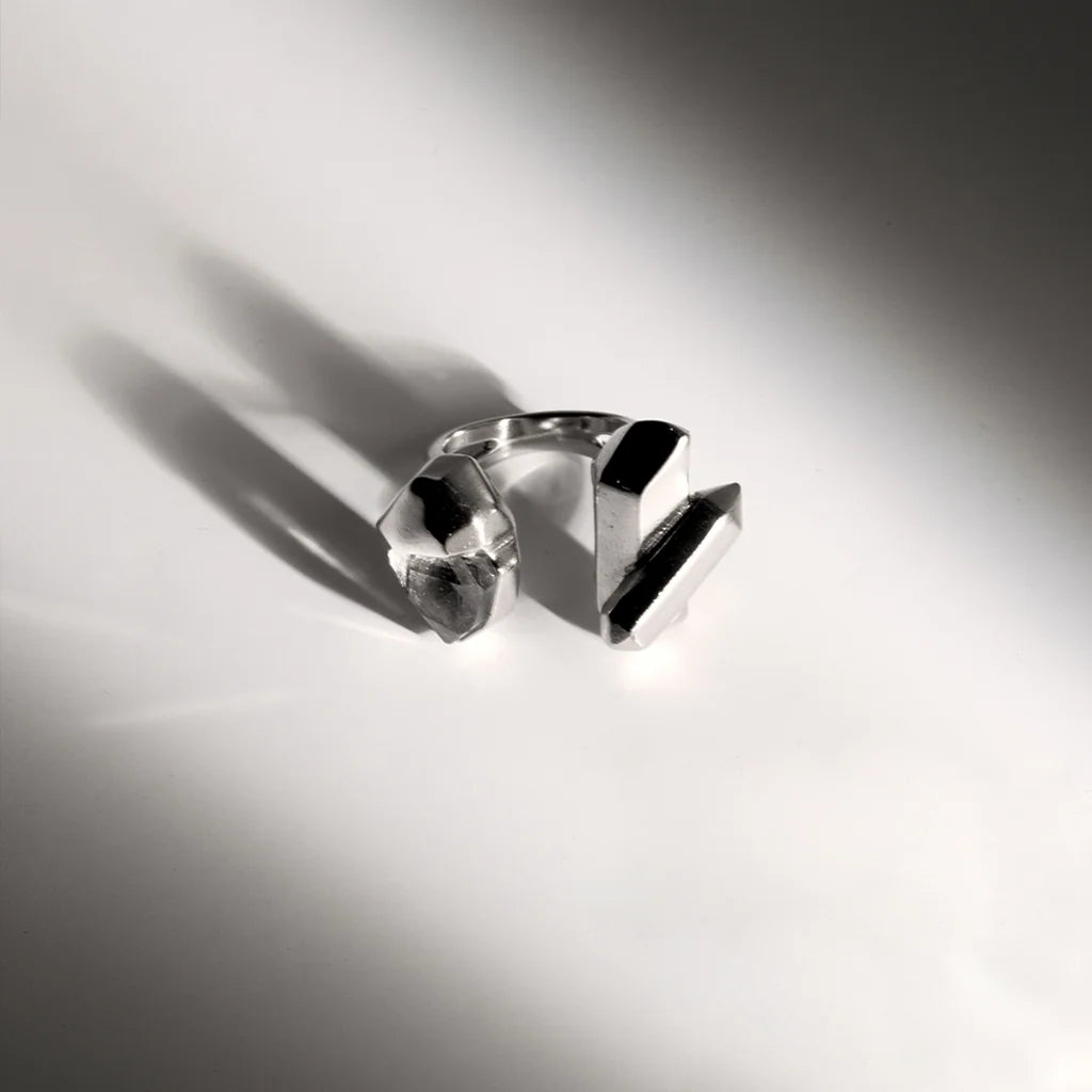Une bague cristaux de roche Turbulence avec design sculptural asymétrique en métal argenté et cristaux aux formes irrégulières.