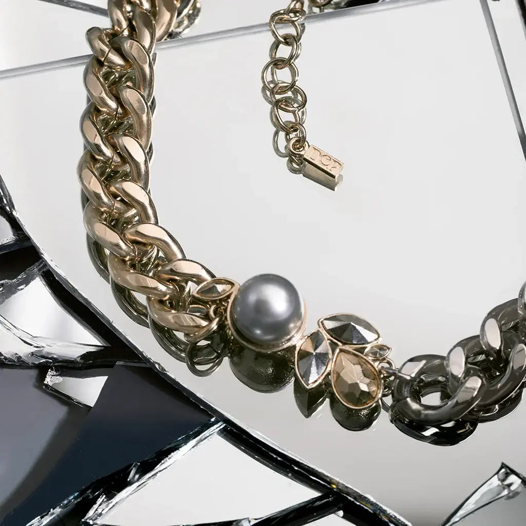 Un collier Fleur Chloé en métal satin doré et argenté brillant, au motif floral central rehaussé d’une perle nacrée en nature morte.