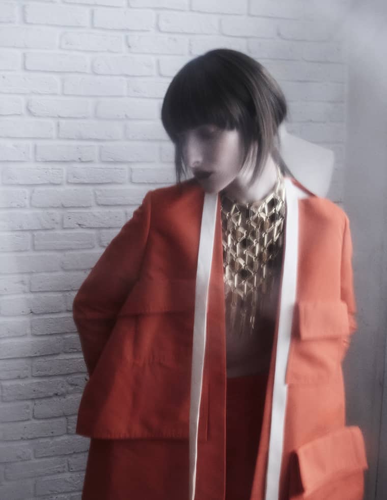 Femme portant un collier plastron Delphine-Charlotte Parmentier, jeu de chaînes dorées contrastant avec une silhouette contemporaine.