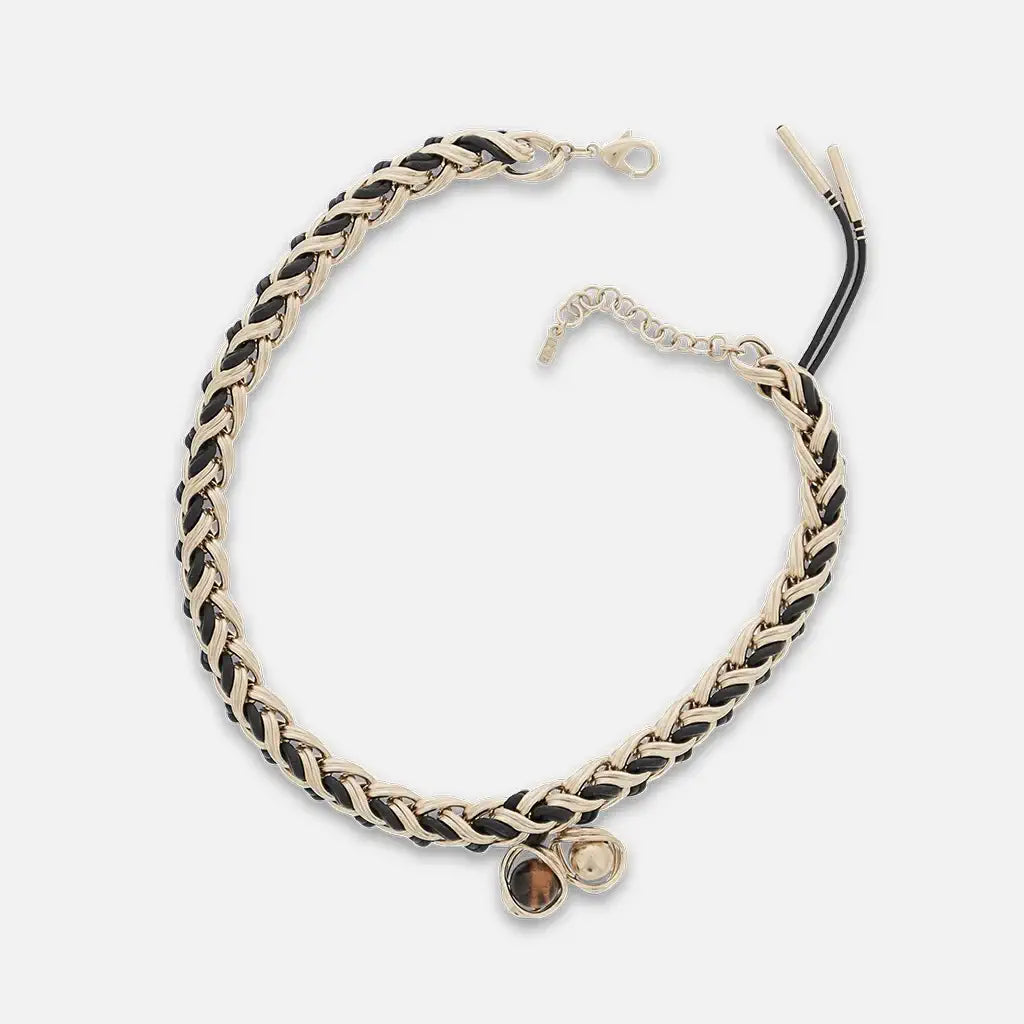 Collier chaîne tressée dorée entrelacée de cuir noir, orné de deux pendentifs ronds sertis.