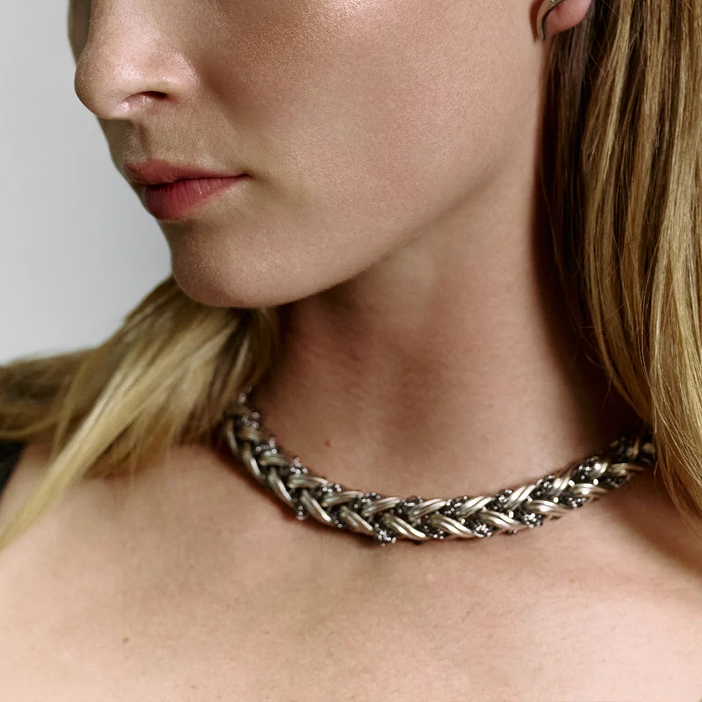 Femme portant le collier tressé Anomalie autour du cou, en métal bicolore argenté et ruthénium.
