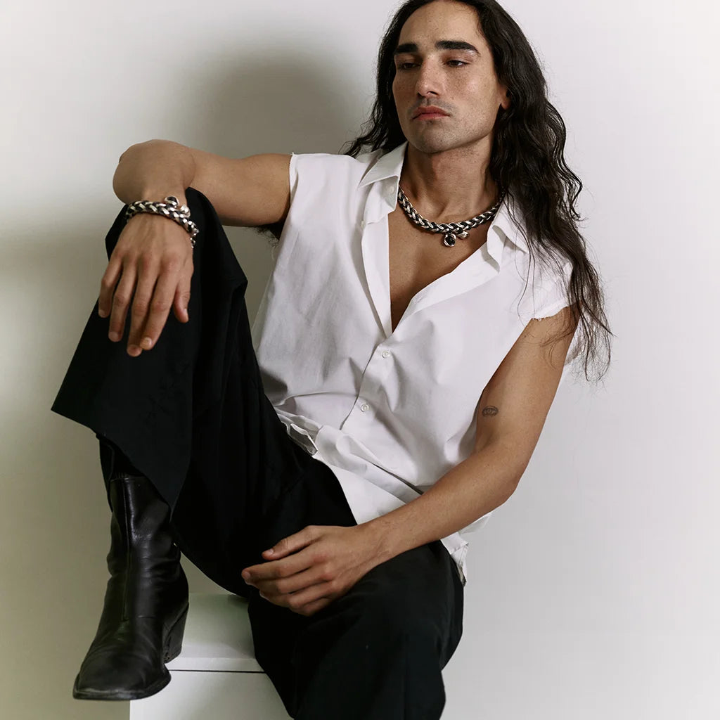 Un homme portant un bracelet cuir tressé Anomalie en chaine satin argentée et cuir noir et perles en verre noire et métal argenté.