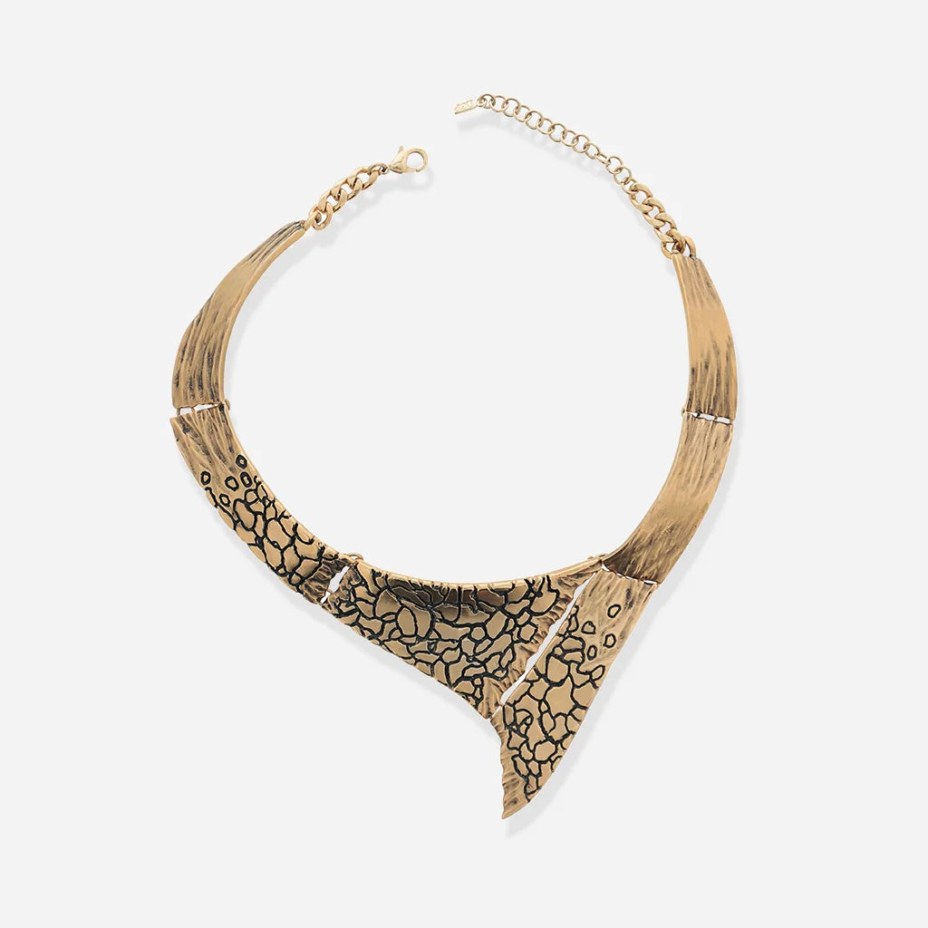 Le collier torque Turbulence en vieux doré, à structure rigide en métal, rehaussé de motifs texturés et finitions vieillies.