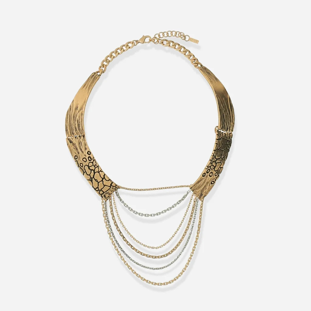 Un collier multi-rangs Trouble à base rigide texturée, avec un drapé de chaînes au design bicolore en vieux doré et argenté.