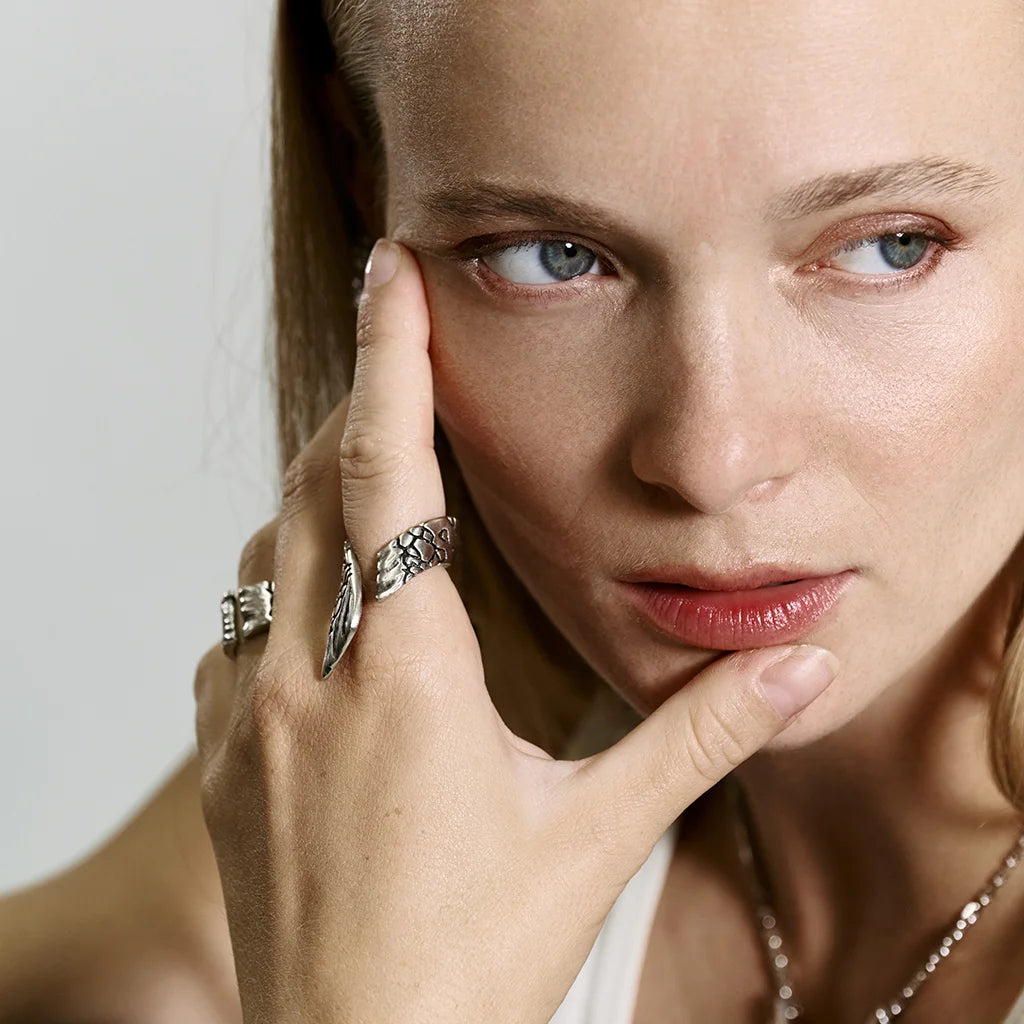 Une femme portant une bague aile Trouble en vieil argenté structuré ouverte aux lignes asymétriques.