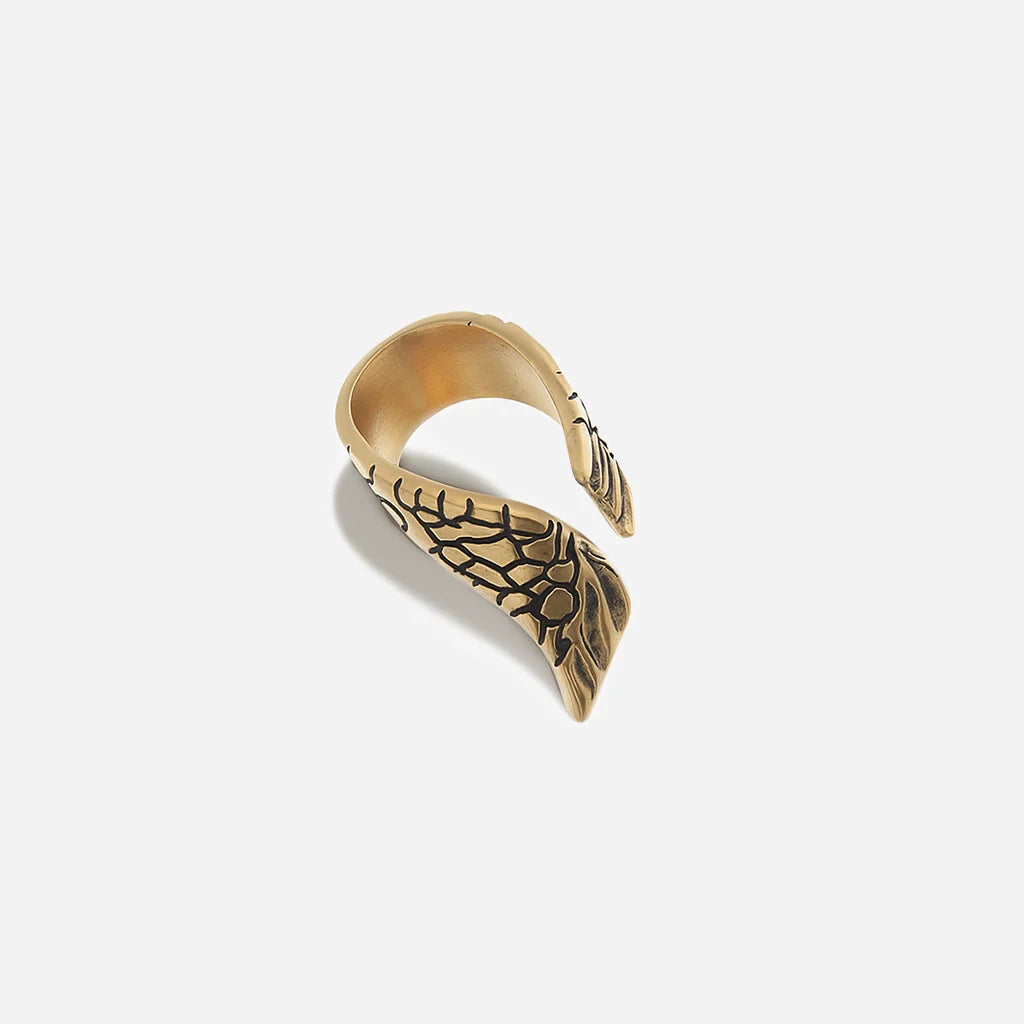 Une bague aile Trouble en métal vieux doré structuré et ouverte aux lignes asymétriques, avec motif de l’aile.