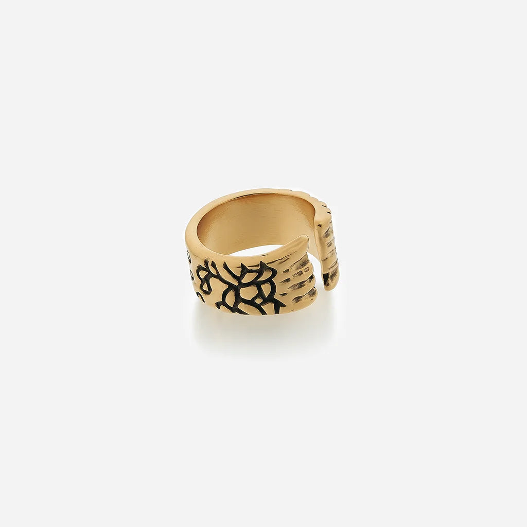 Bague texturée Trouble en métal vieil doré ouverte et structurée, avec motif craquelé rappelant une matière fissurée.