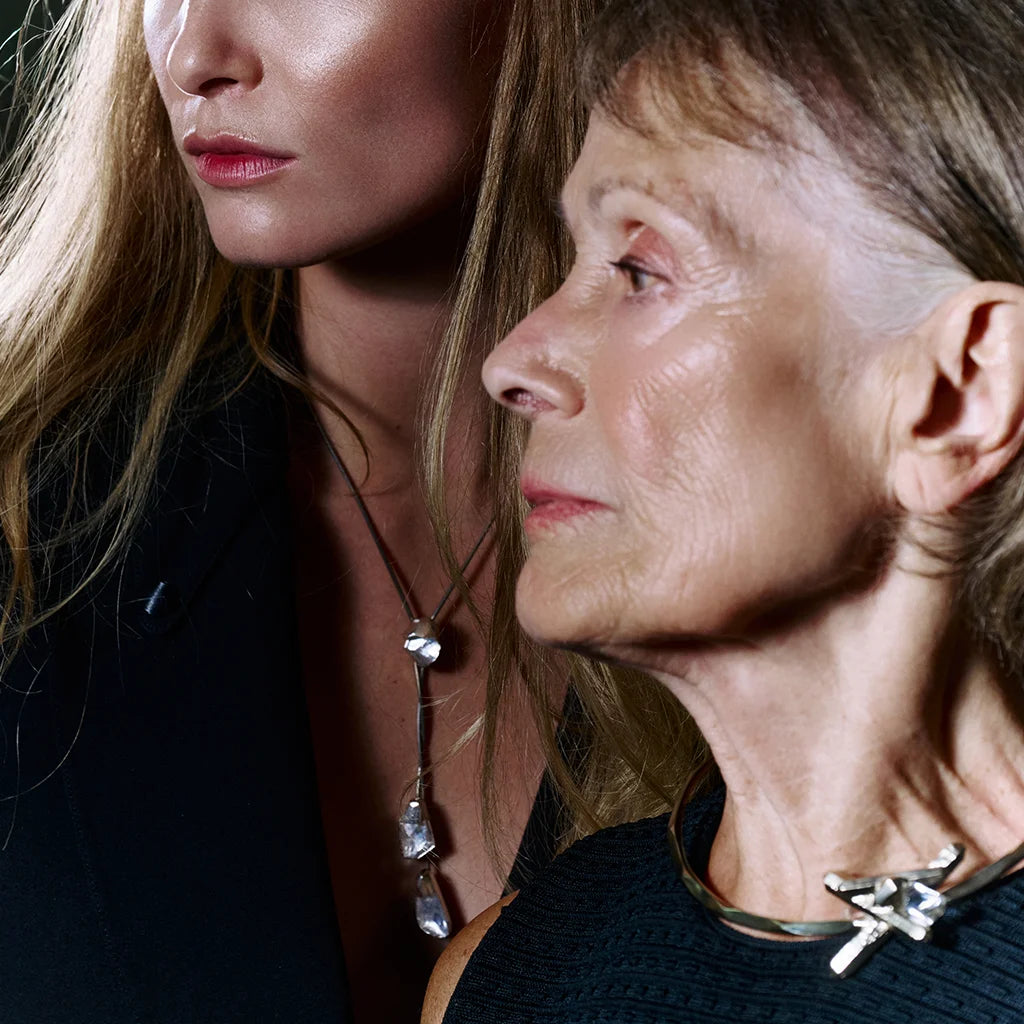 Collier torque et collier cravate Turbulence en métal satiné avec motif en cristal de roche, portés par deux femmes. 
