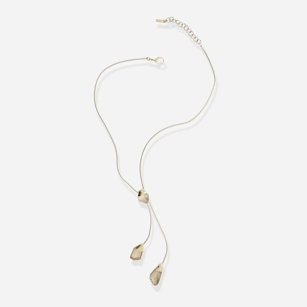 Le collier cravate en métal doré pour femme présente trois éléments facettés suspendus à une chaîne souple.