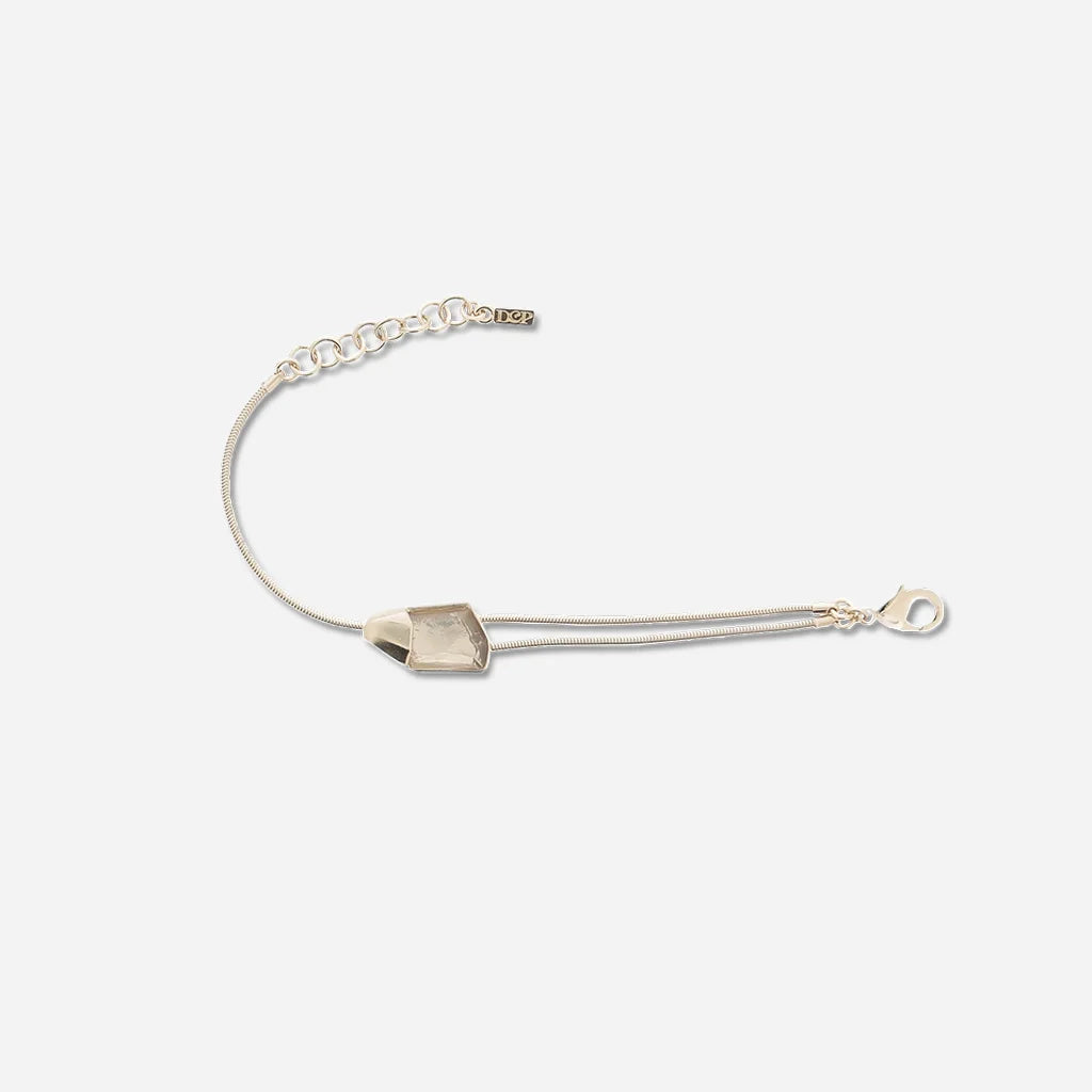 Bracelet cristal de roche Turbulence aux lignes asymétriques, monté sur une double chaîne fine en métal doré.