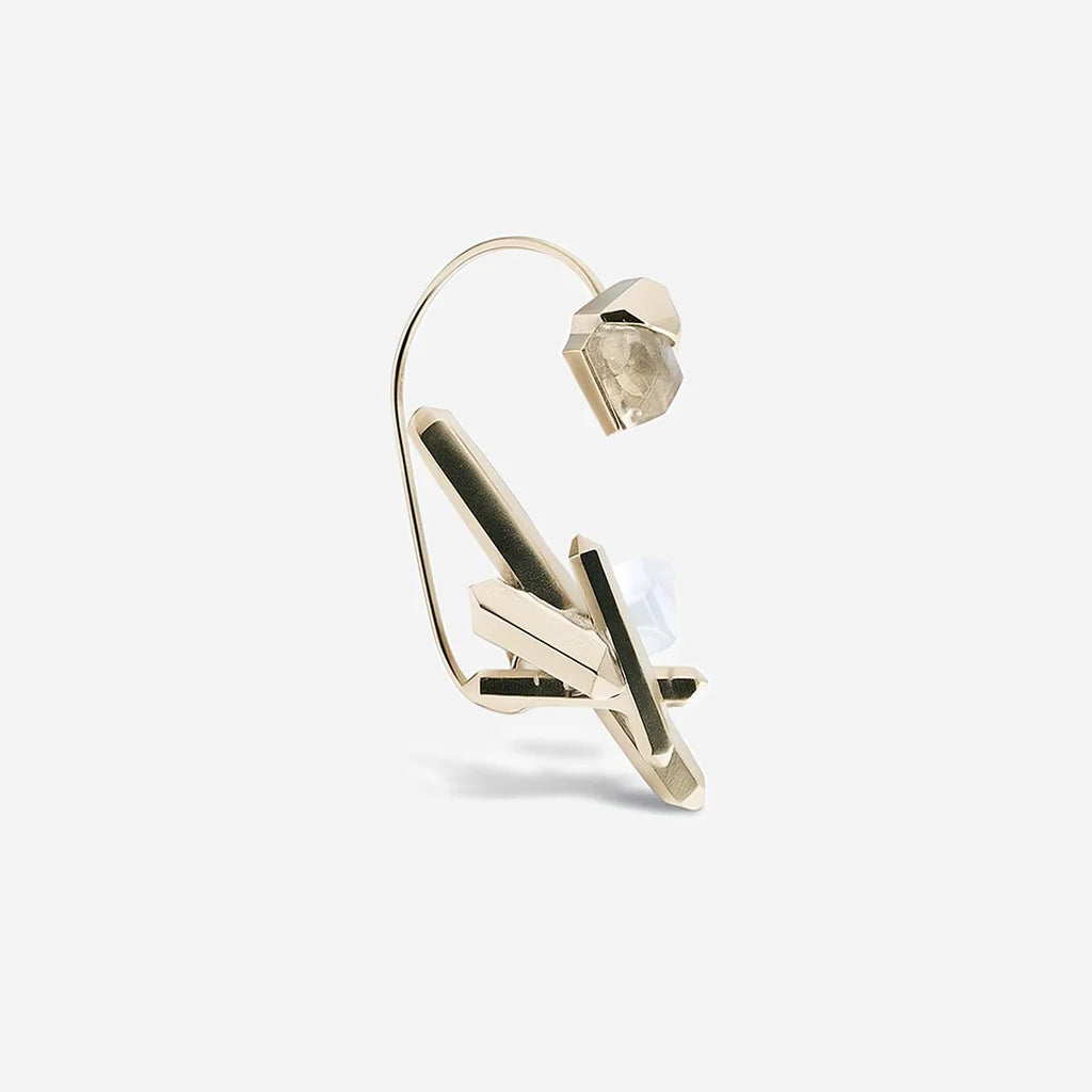 Bijou d'oreille créateur Turbulence en métal doré avec deux volumes cristallins reliés par une tige.