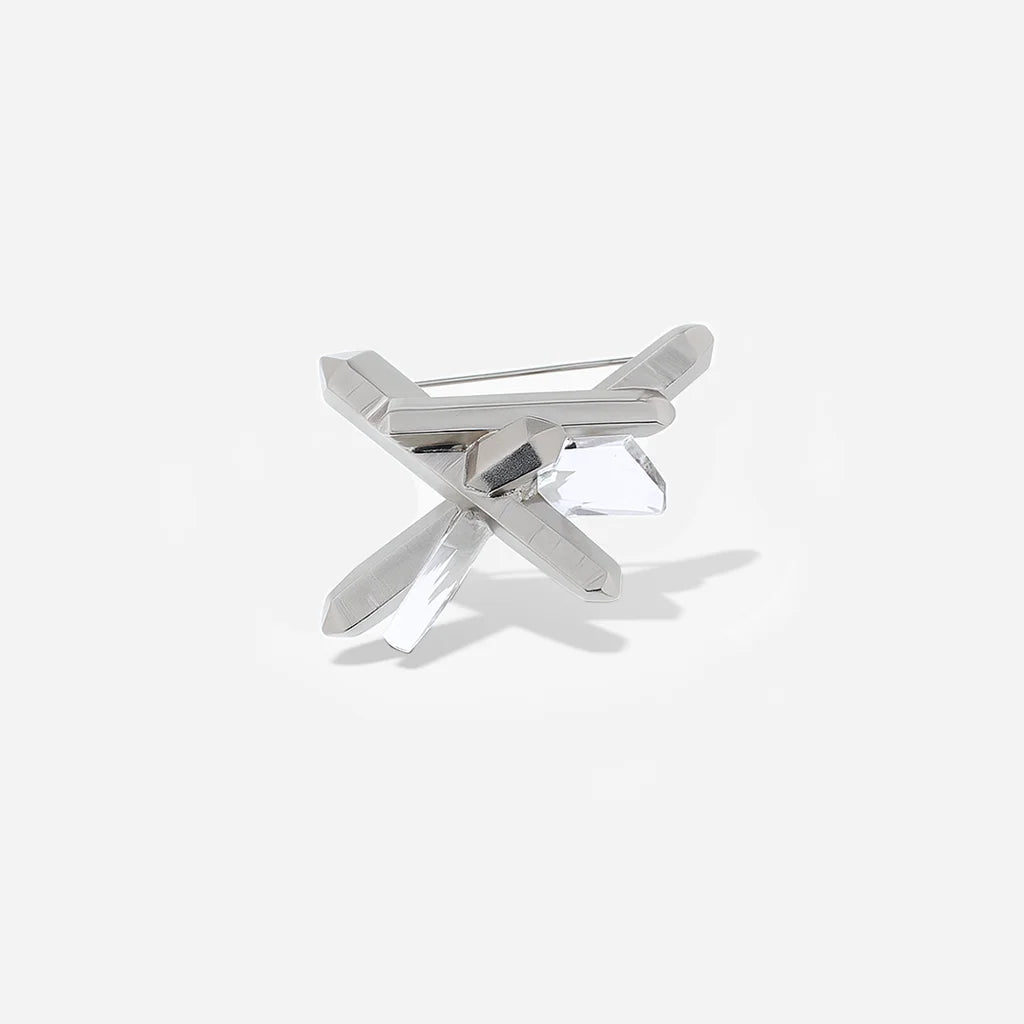 La broche cristal de roche Turbulence en métal argenté présente une forme asymétrique.