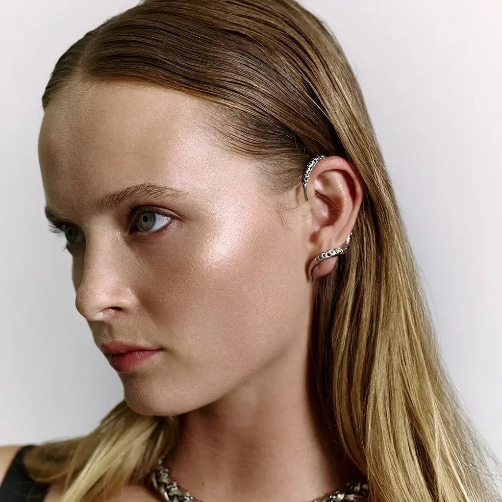 Une femme portant une boucle d'oreille Serpent N26 ornée de strass noirs et enroulé autour de son oreille.