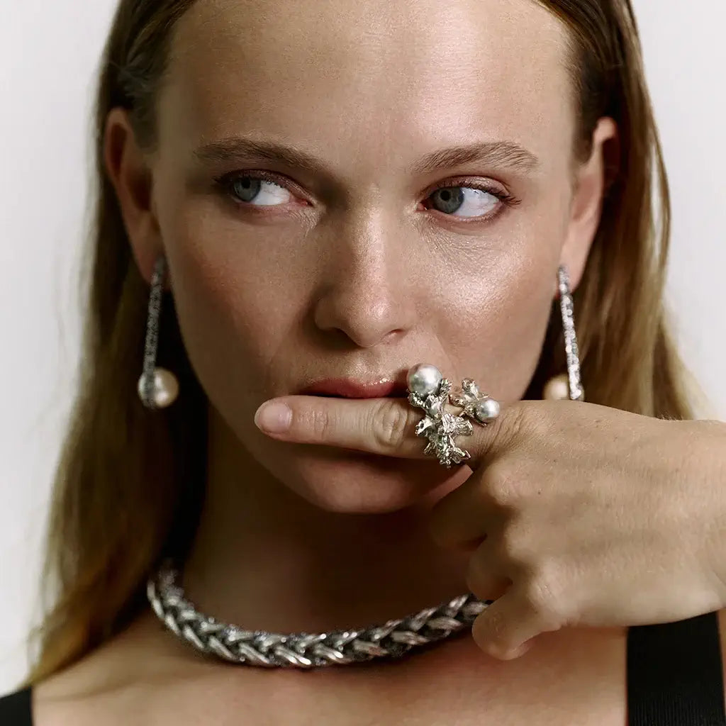 Femme portant une bague perle Nature en métal doré sculpturale, enrichie de deux perles en cristal laqué.