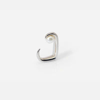 La bague Noe en métal argenté porte une perle en suspension, rehaussée d'un cristal laqué crème.
