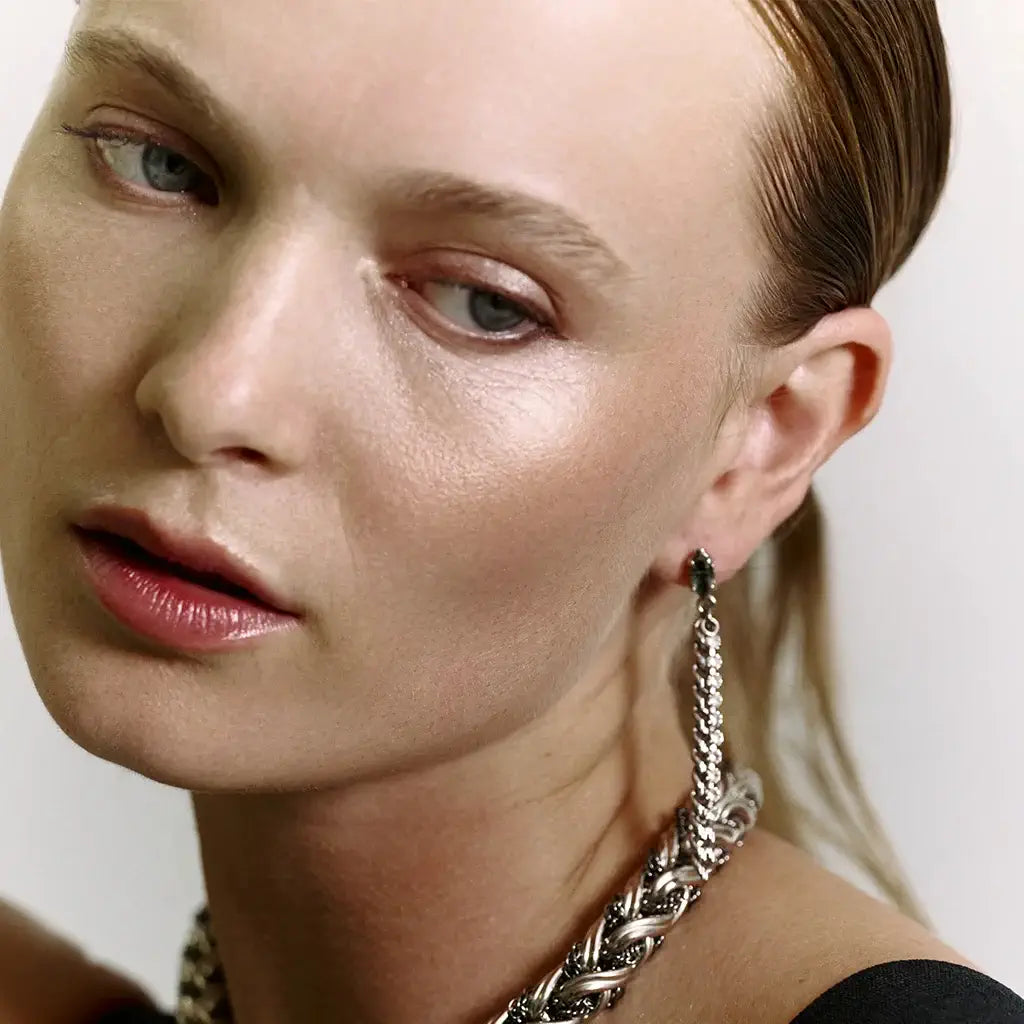 Femme portant des boucles Vénus en métal doré, combinant une chaîne gourmette et une délicate chaînette de strass.
