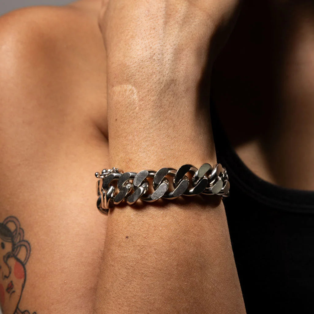 Bracelet gourmette épais en métal argenté porté au poignet, gros plan au style audacieux et contemporain.