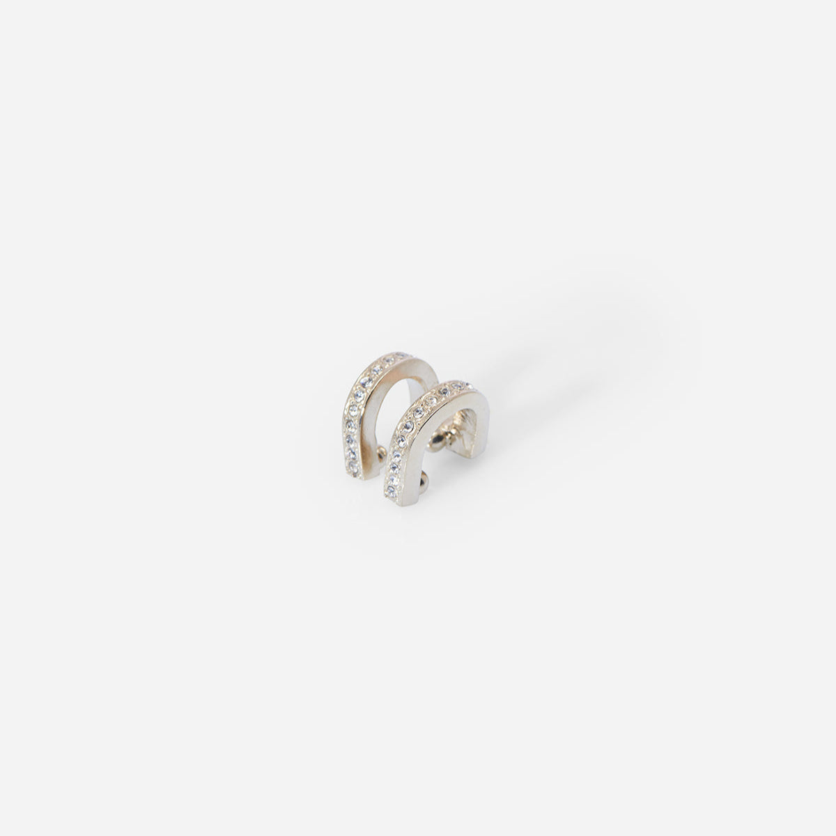 Bijou d’oreille Eden en métal satiné doré, double barrette arrondie ornée de strass cristaux, au design graphique.