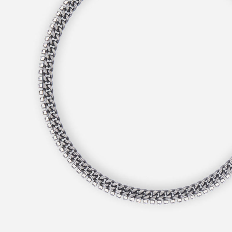 Collier gourmette Vénus en métal satiné ruthénium, avec chaîne texturée et seconde chaîne ornée de strass.